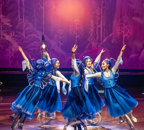Performers in blue costumes on unicycles during a Las Vegas entertainment show.