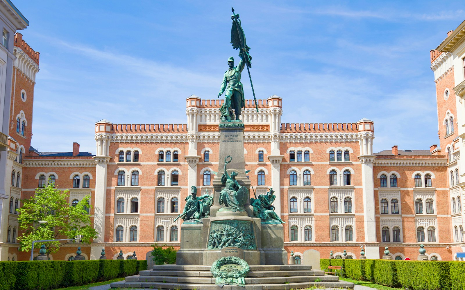 Rossauer Barracks in Vienna with historic architecture and lush green trees in the foreground.