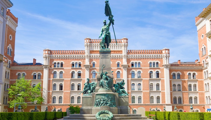 Rossauer Barracks in Vienna with historic architecture and lush green trees in the foreground.