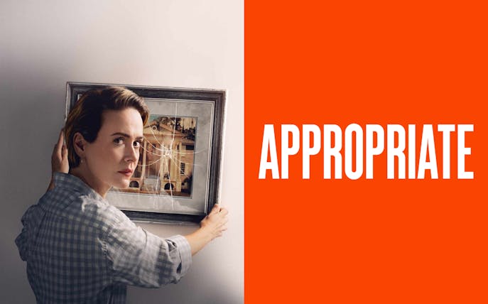 A person holding a cracked picture frame with a building image.