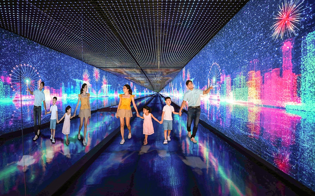 Family exploring digital art tunnel at Singapore Flyer with cityscape and fireworks.