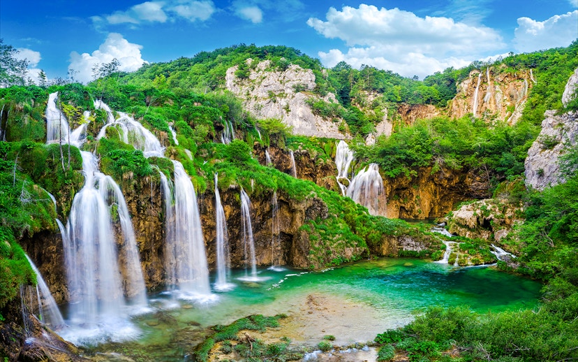 Waterfalls cascading into a turquoise lake at Plitvice Lakes National Park, Croatia.