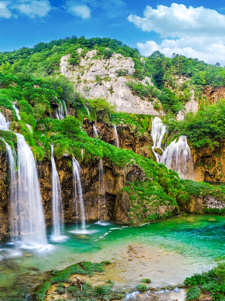 Waterfalls cascading into a turquoise lake at Plitvice Lakes National Park, Croatia.