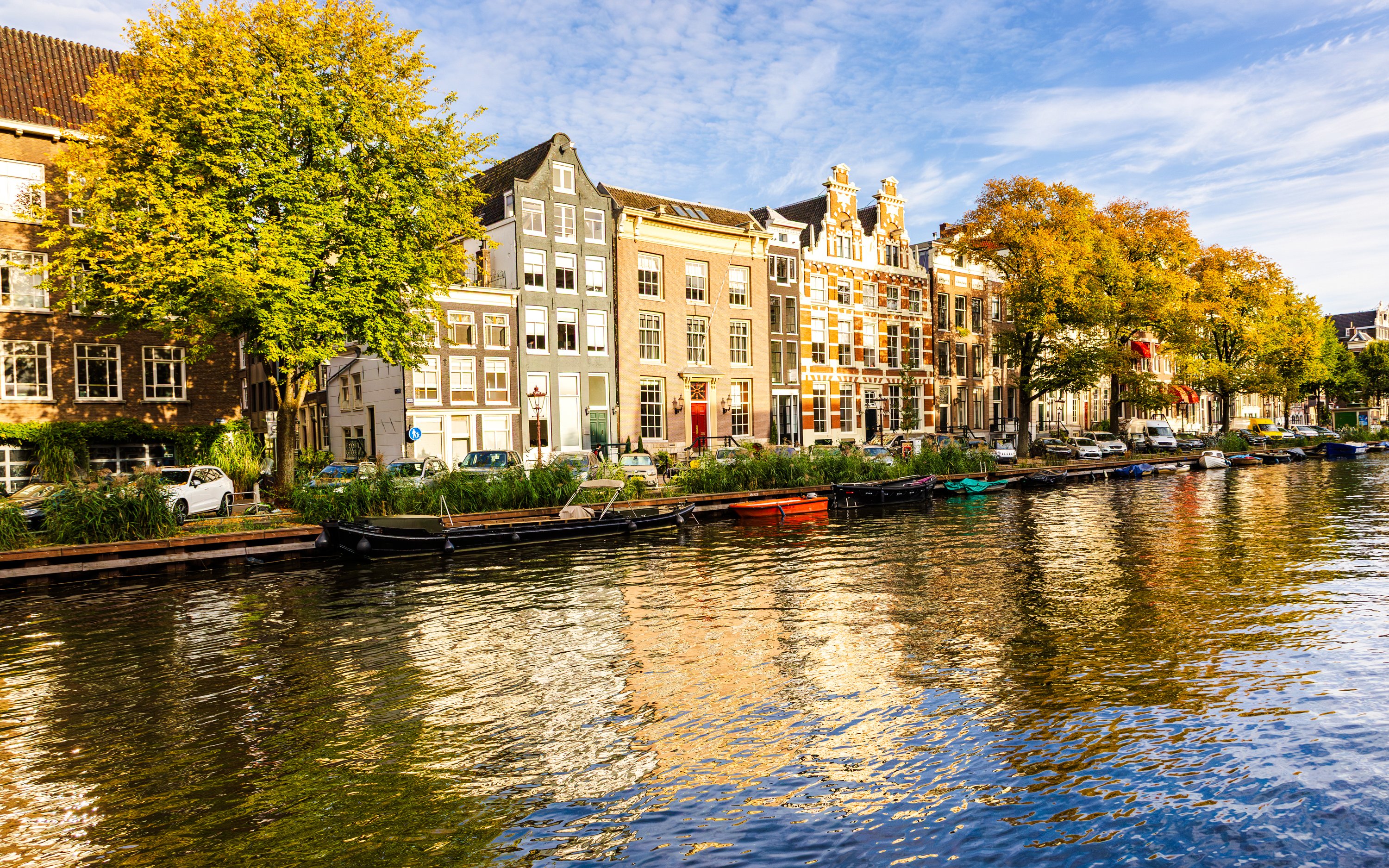 Houses along the Singel Canal in Amsterdam with trees and boats.