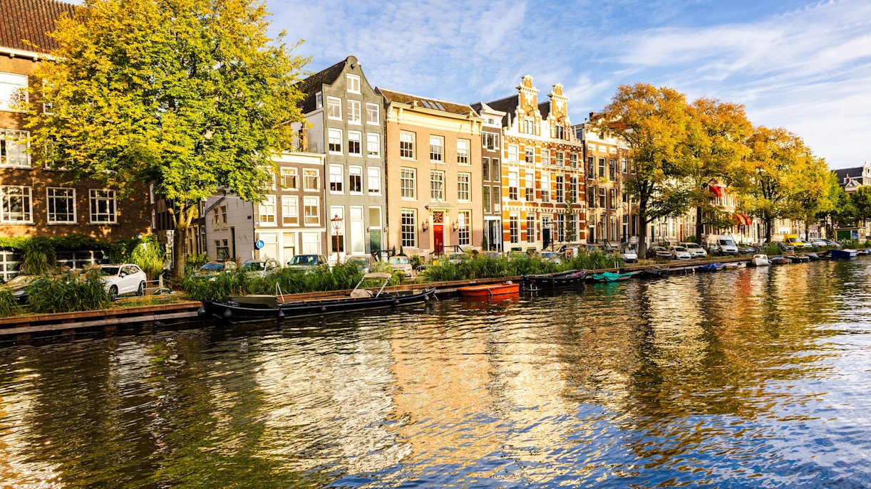 Houses along the Singel Canal in Amsterdam with trees and boats.