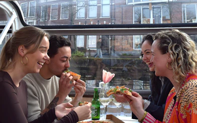 Group enjoying Nolita pizza on Haarlem canal dinner cruise.