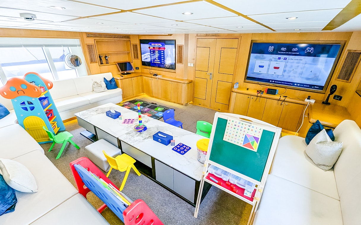 Children's play area inside yacht with toys, games, and educational board.