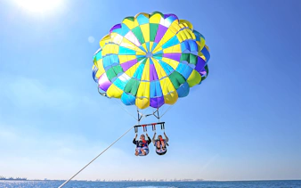 Parasailing over the sea in Dubai with colorful parachute.