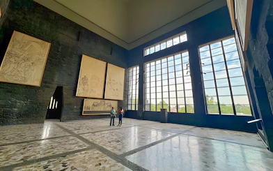 Interior of Anahuacalli Museum with large windows and mural art on dark stone walls.