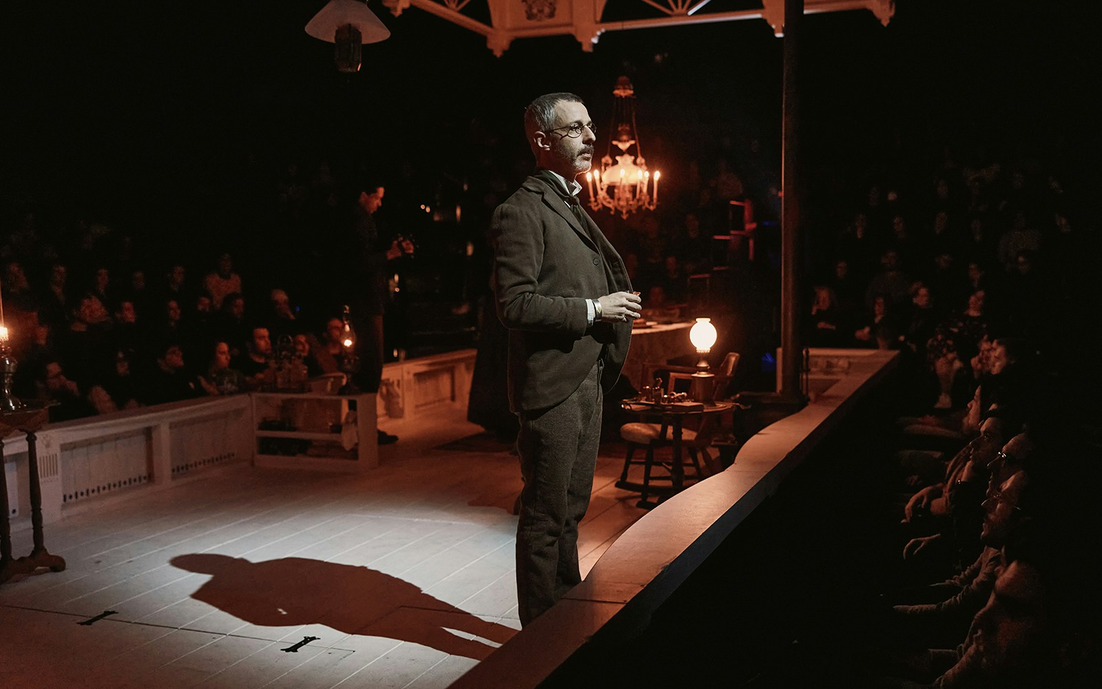 Actor performing "An Enemy of the People" on stage with audience in background.