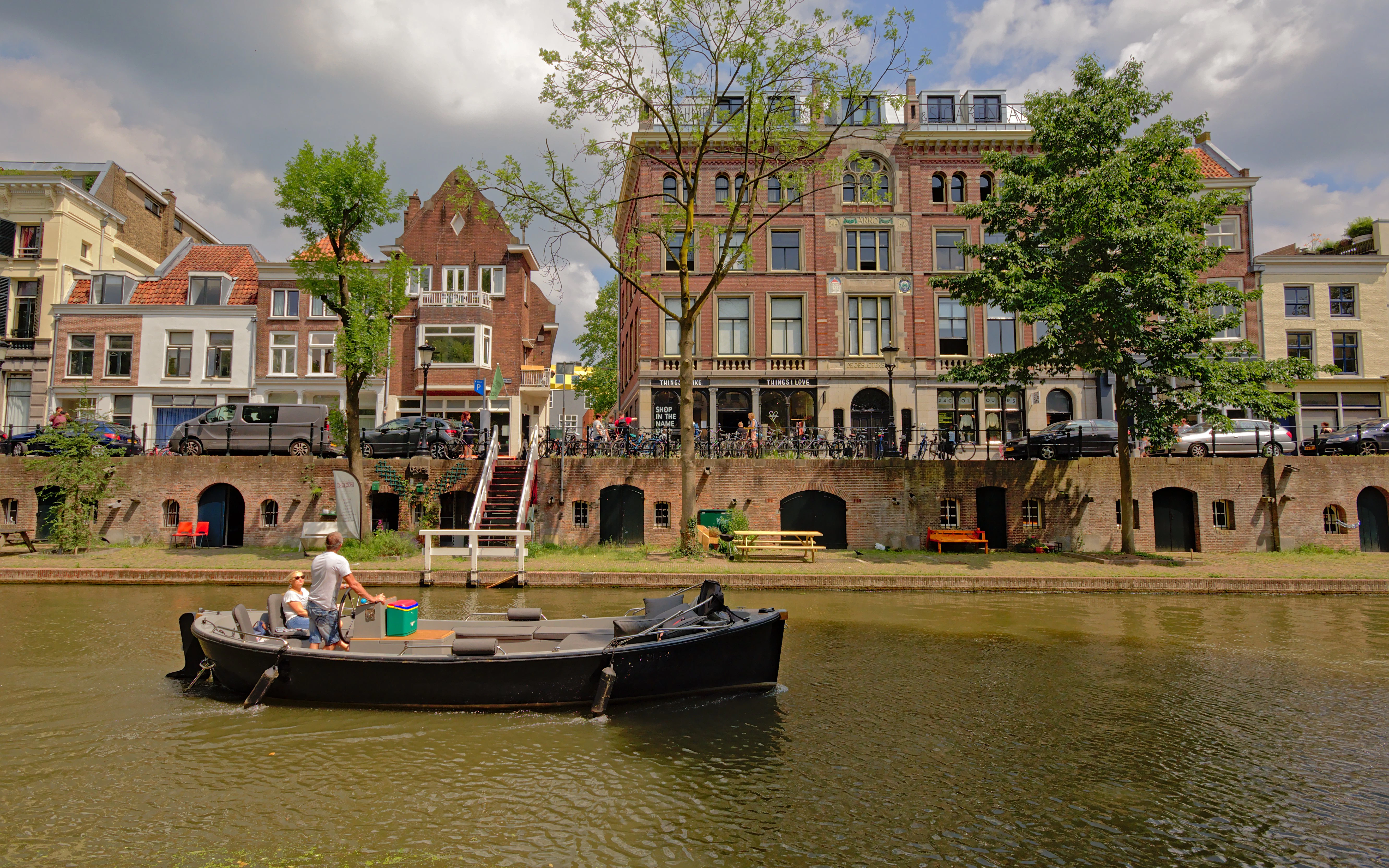 Boat on old canal in Utrecht with Dutch houses and cellars on wharf.