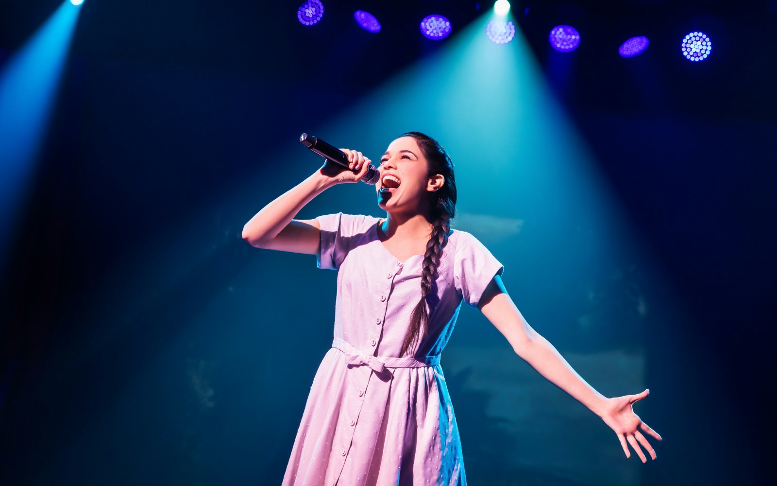 Performer singing on stage during "Here Lies Love" musical.
