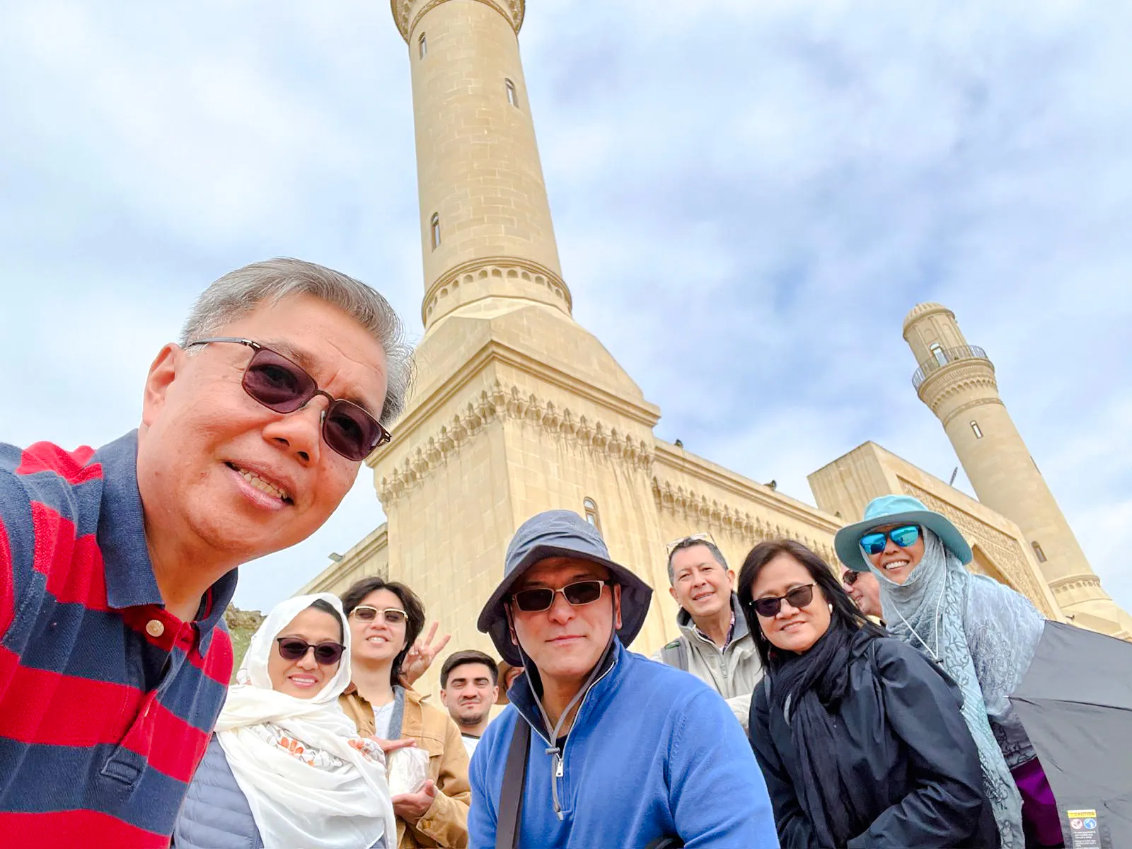 Tour group at Gobustan National Park with mosque in background, Baku.