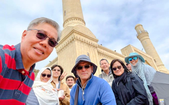 Tour group at Gobustan National Park with mosque in background, Baku.