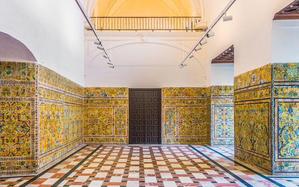 Alcazar of Seville interior with intricate tilework and arched ceiling.