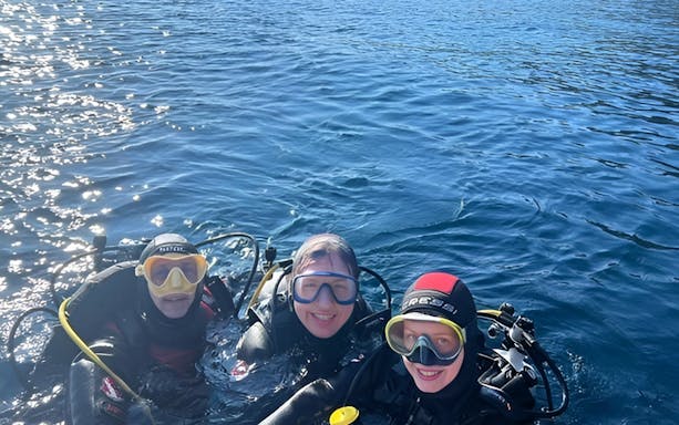 Scuba divers in the waters of Aci Castello, Italy.