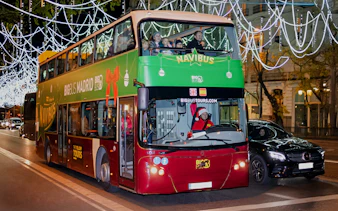 Double-decker bus on Madrid Navibus Christmas Tour with festive lights.