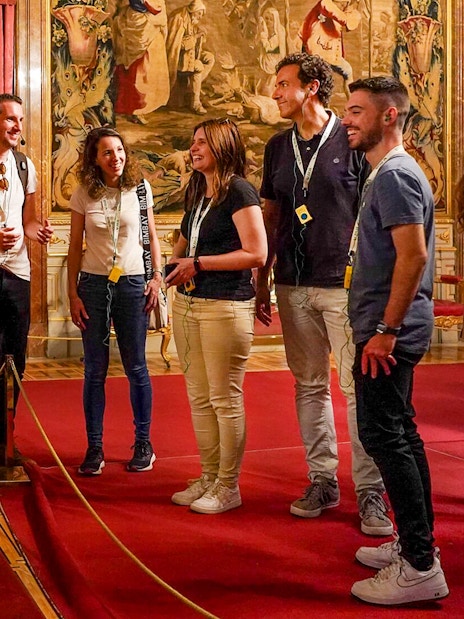 Tour group admiring ornate throne room in the Royal Palace of Madrid, Spain.