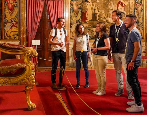 Tour group admiring ornate throne room in the Royal Palace of Madrid, Spain.