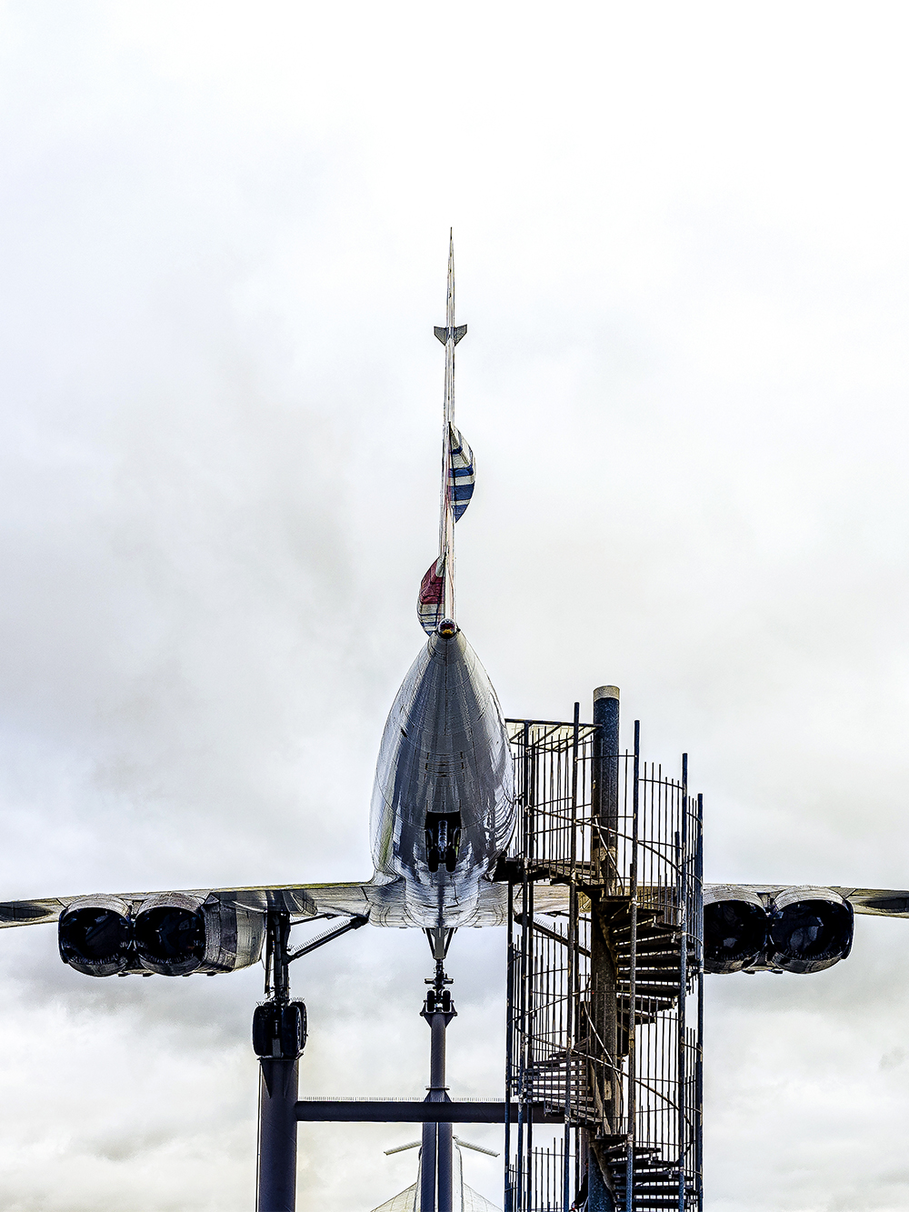 Concorde aircraft displayed at an aviation museum with spiral staircase access.
