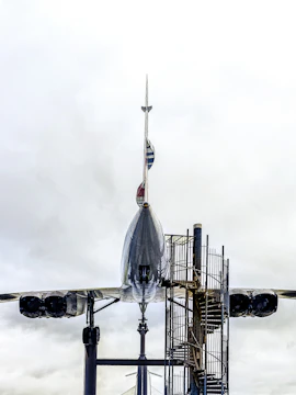 Concorde aircraft displayed at an aviation museum with spiral staircase access.