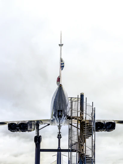 Concorde aircraft displayed at an aviation museum with spiral staircase access.