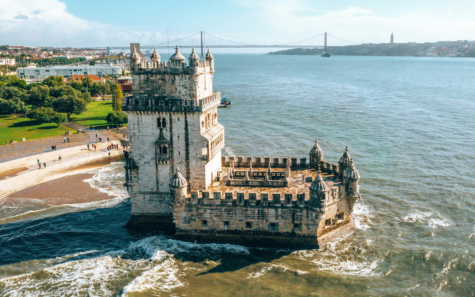 Belem Tower in Lisbon, Portugal, with Tagus River and 25 de Abril Bridge in the background.