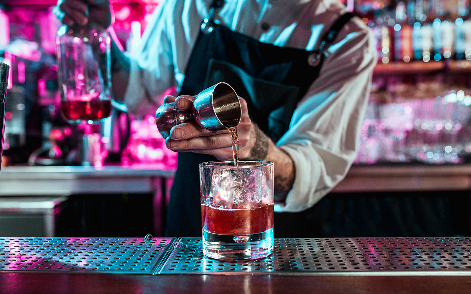 Person pouring wine into glass at the bar counter