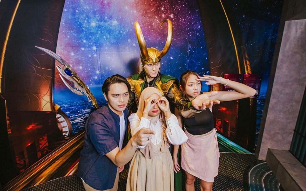 Visitors posing with Loki wax figure at Madame Tussauds Singapore.