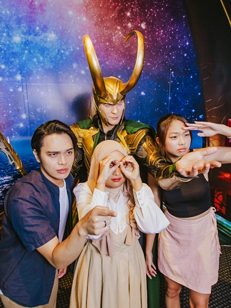 Visitors posing with Loki wax figure at Madame Tussauds Singapore.
