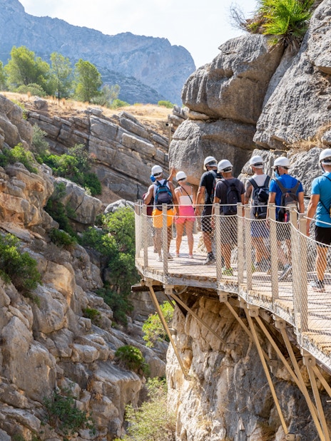 Group walking on Caminito del Rey path in rocky gorge, Andalusia, Spain.