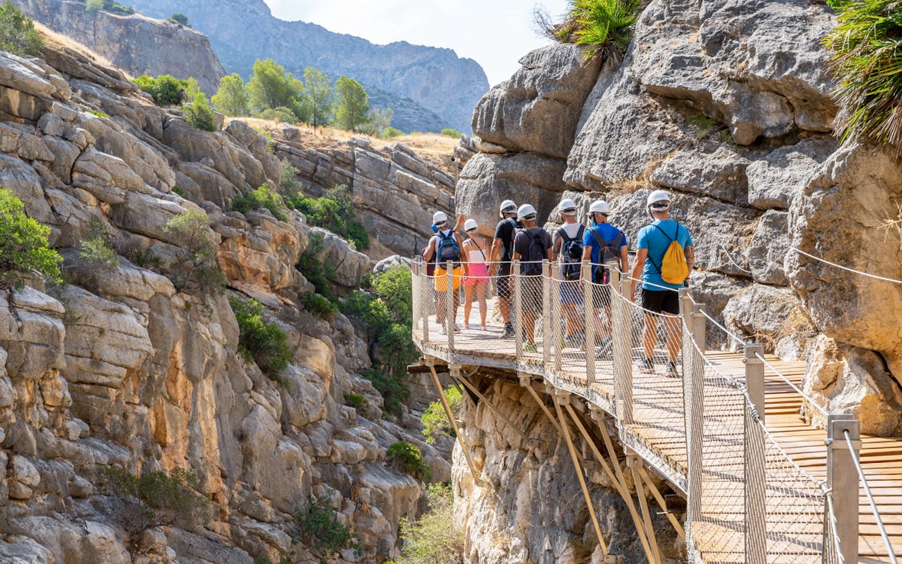 Group walking on Caminito del Rey path in rocky gorge, Andalusia, Spain.
