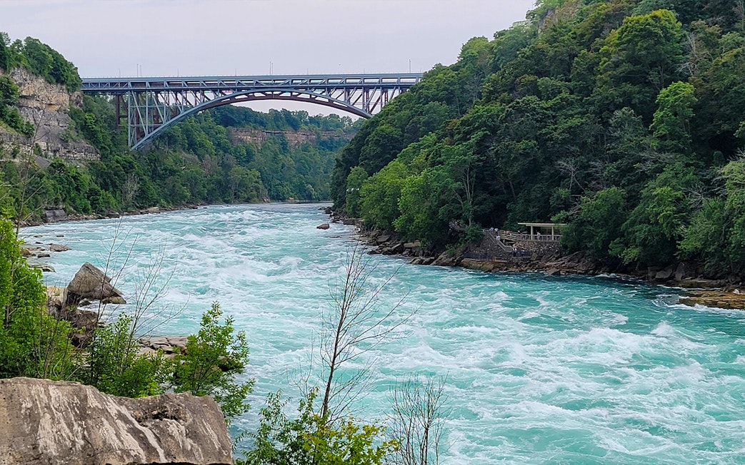 Niagara River flowing through Whirlpool State Park with a bridge in the background, USA.