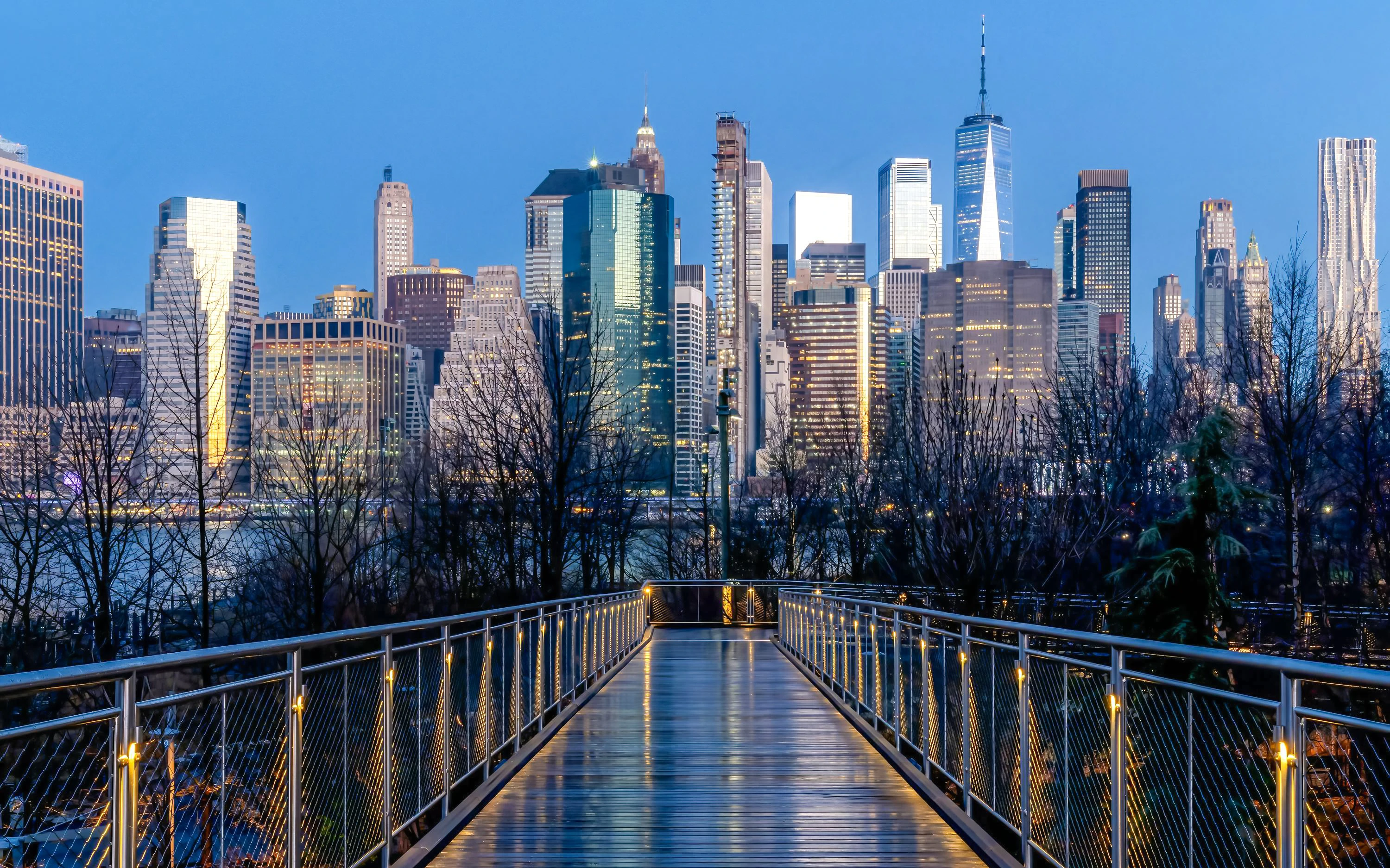 Squibb Park Bridge at sunrise with New York City skyline in the background.