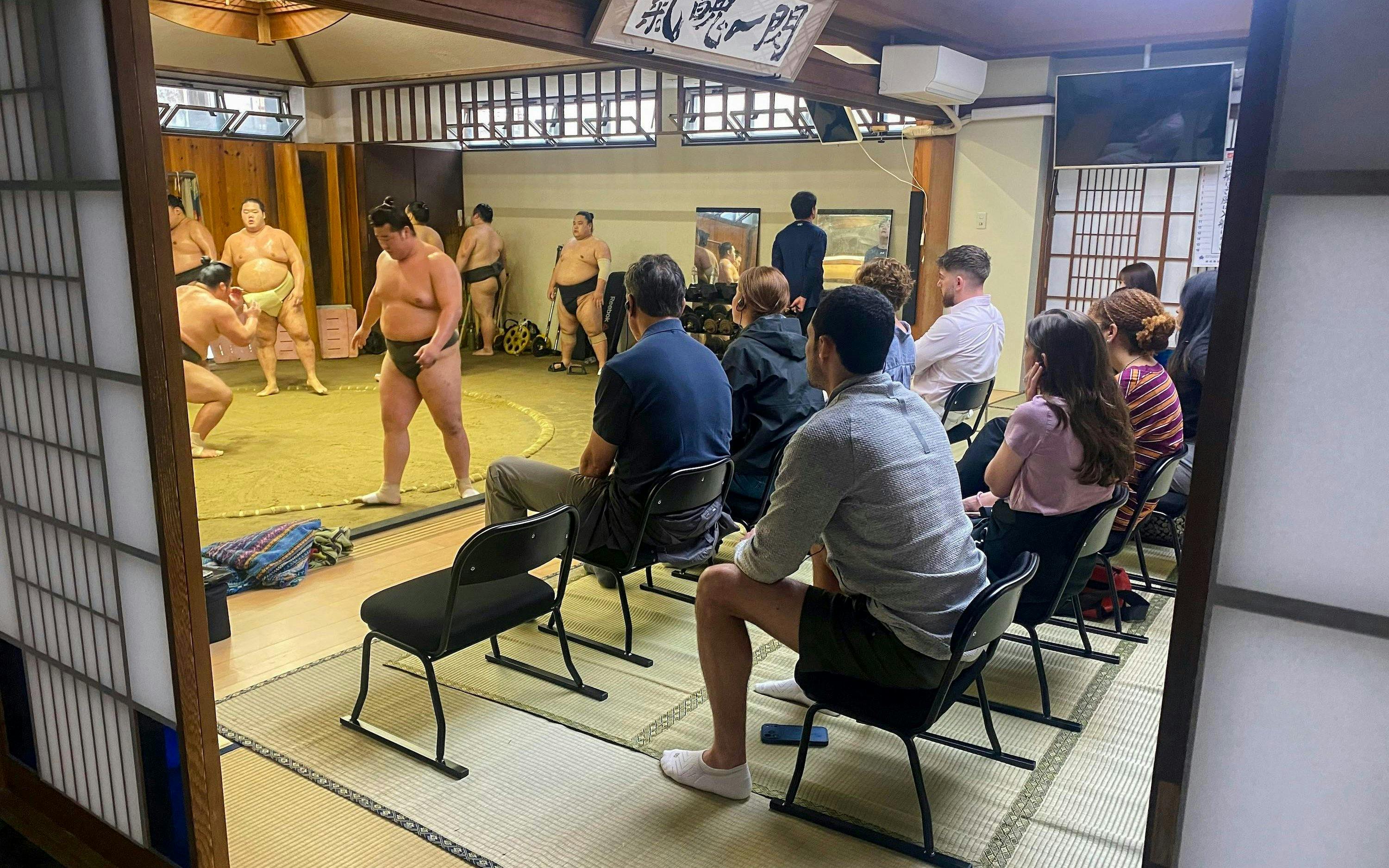 Sumo wrestlers practicing in a dojo with spectators watching in Asakusa.