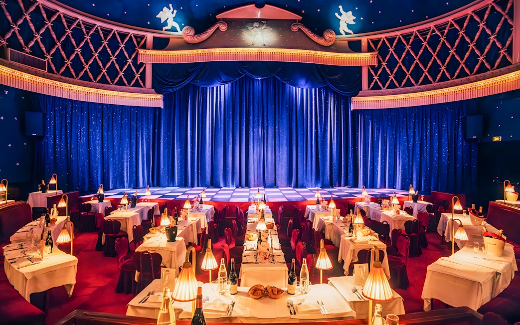 Cabaret La Nouvelle Eve stage with tables set for a champagne spectacle in Paris.