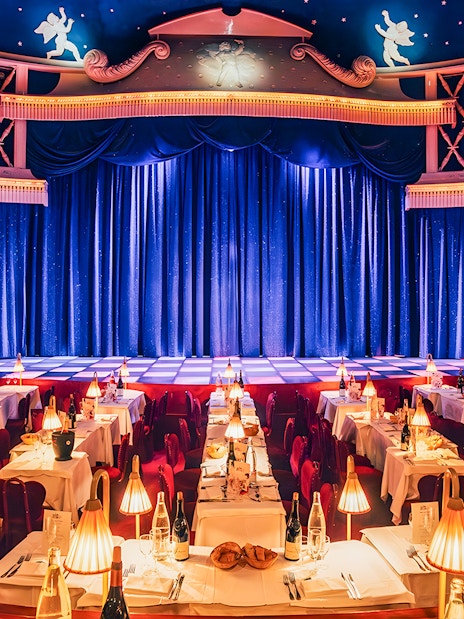 Cabaret La Nouvelle Eve stage with tables set for a champagne spectacle in Paris.