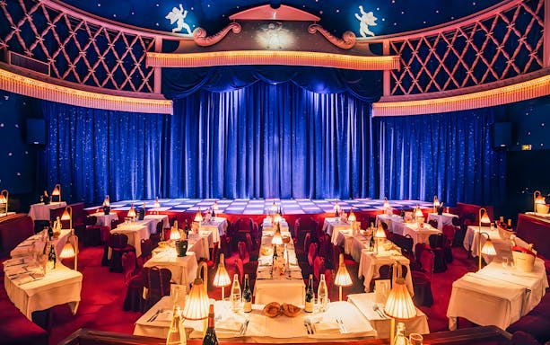 Cabaret La Nouvelle Eve stage with tables set for a champagne spectacle in Paris.