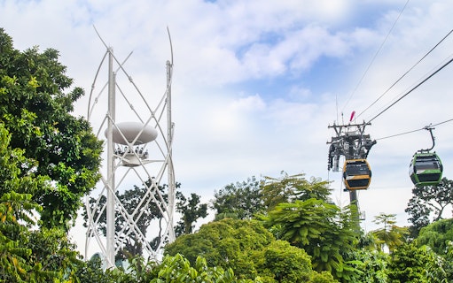 SkyHelix Sentosa and Singapore Cable Car over lush greenery.