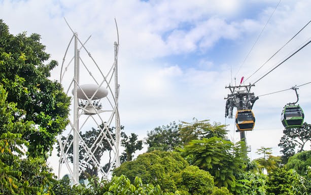 SkyHelix Sentosa and Singapore Cable Car over lush greenery.
