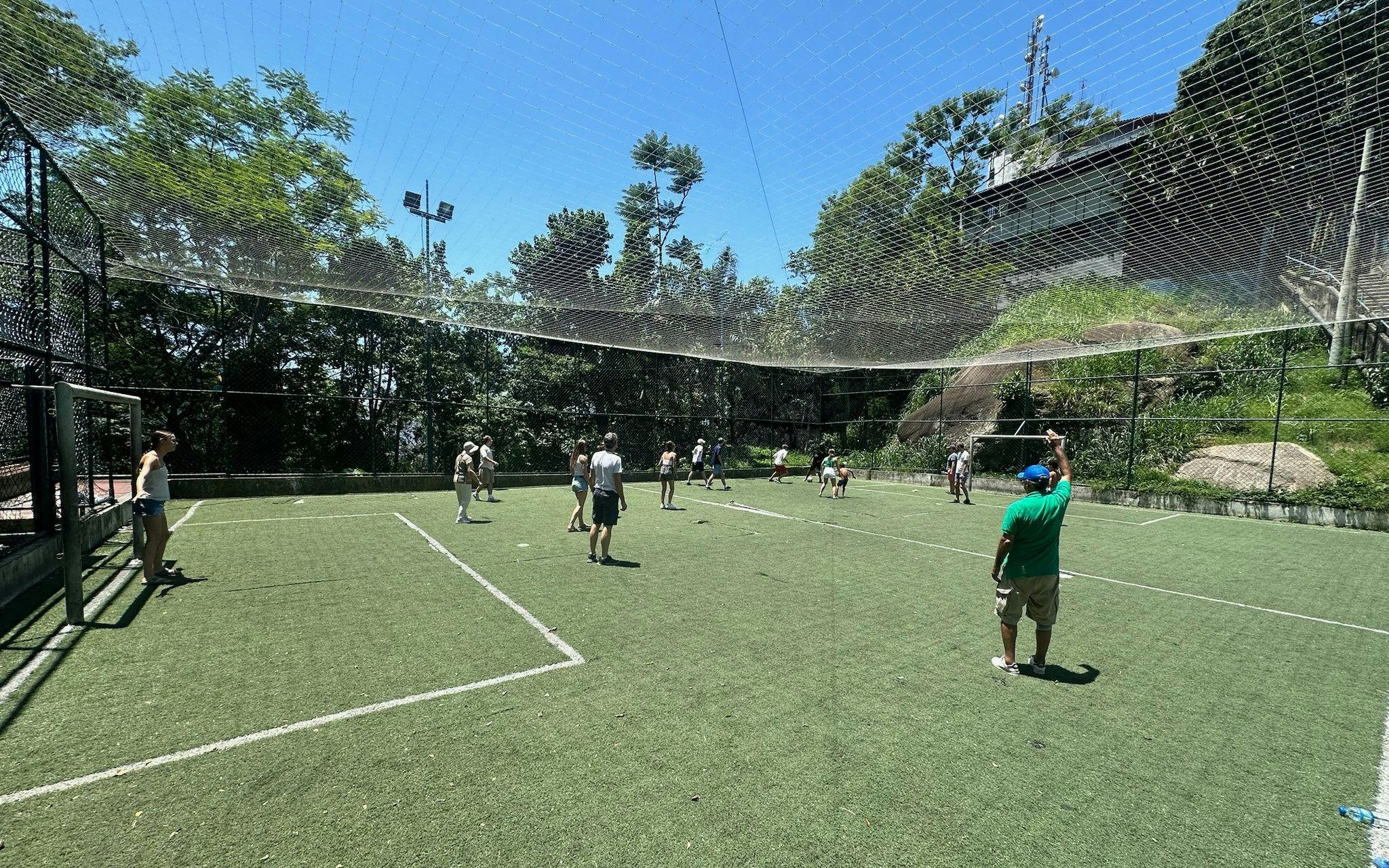 Tourists playing football with a guide on a turf field in Santa Marta, Rio.