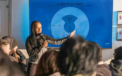 Female guide explaining whale watching code of conduct to tour group.