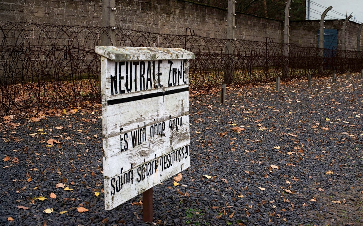 Barbed wire fence and warning sign at Sachsenhausen Concentration Camp, Germany.