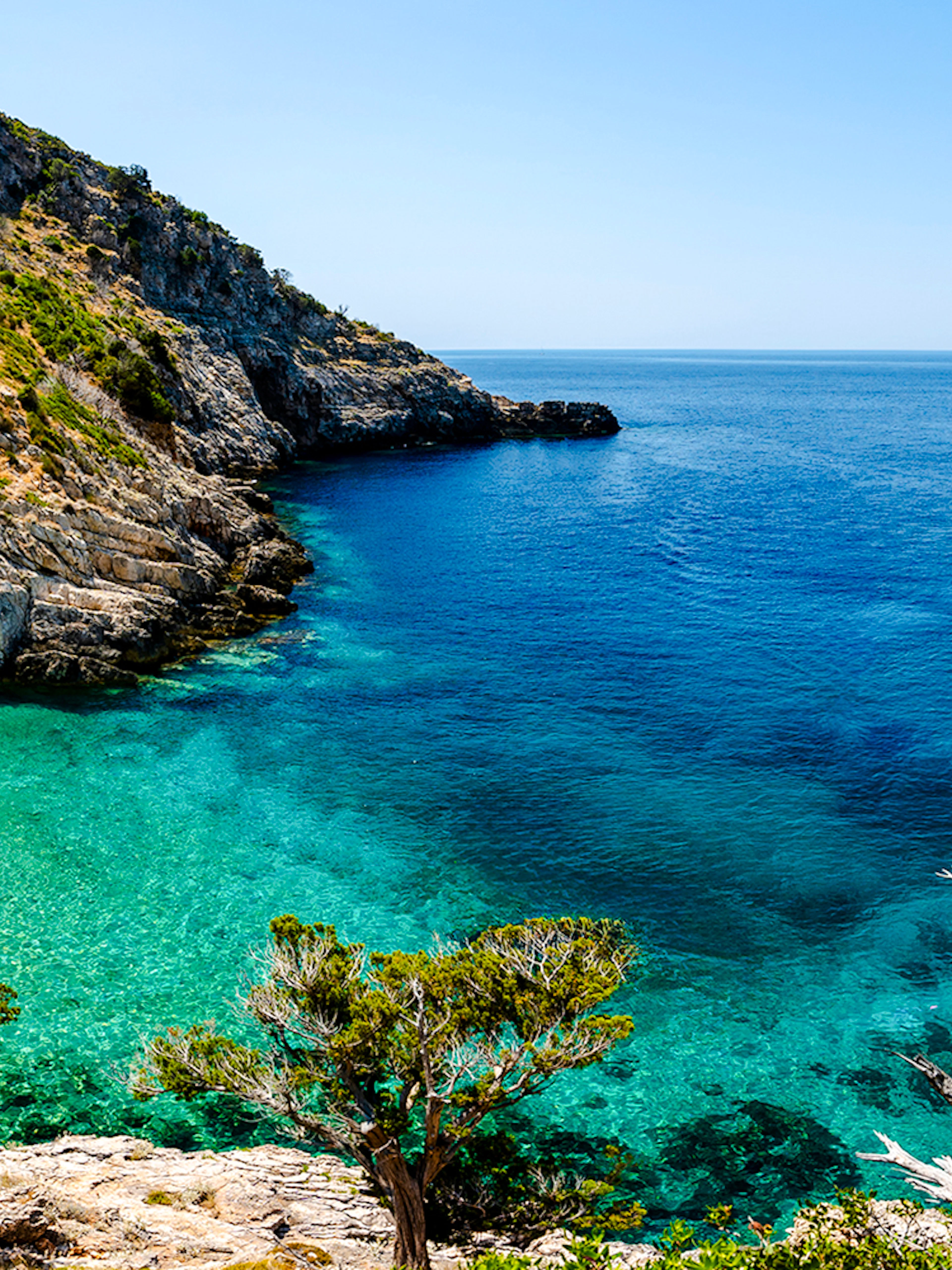 Dafina Bay with clear turquoise waters and rocky cliffs.