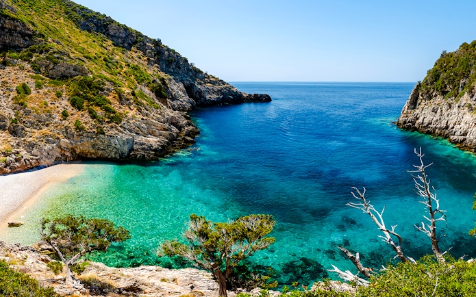 Dafina Bay with clear turquoise waters and rocky cliffs.