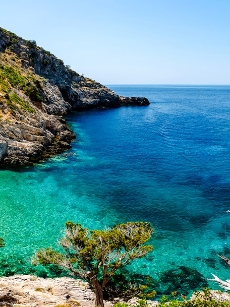 Dafina Bay with clear turquoise waters and rocky cliffs.