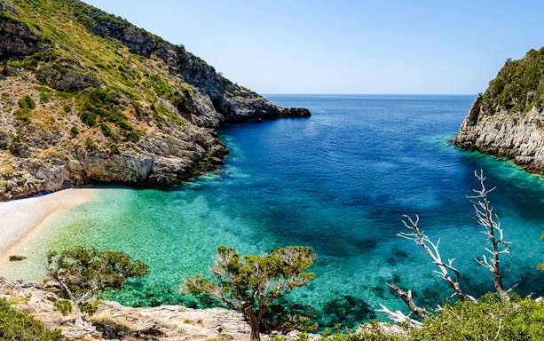 Dafina Bay with clear turquoise waters and rocky cliffs.