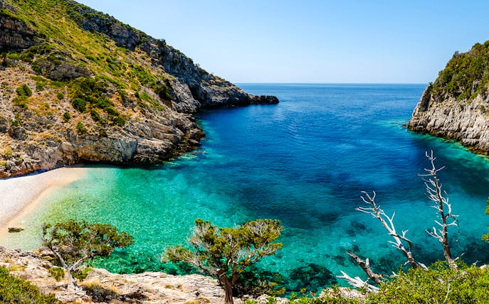 Dafina Bay with clear turquoise waters and rocky cliffs.