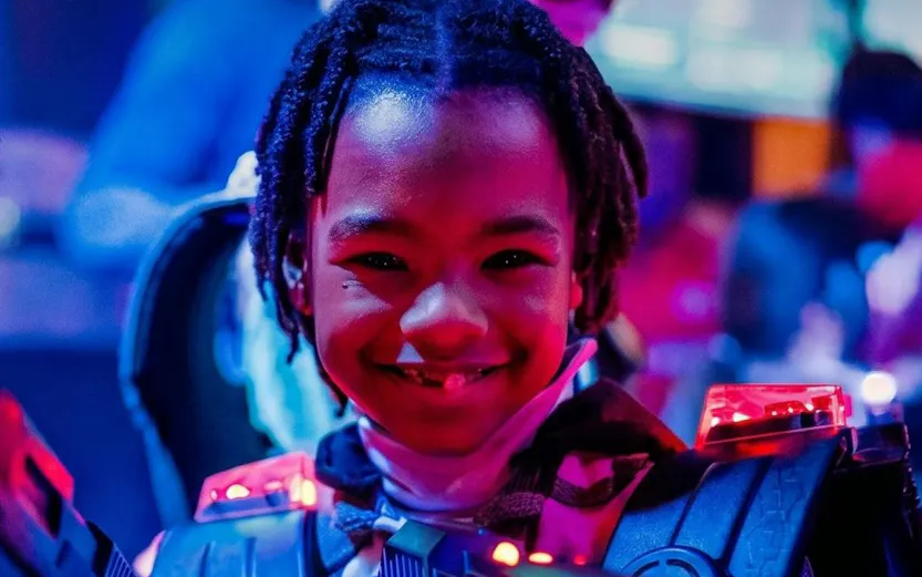 Child playing laser tag at Lasergame Rotterdam with glowing gear.