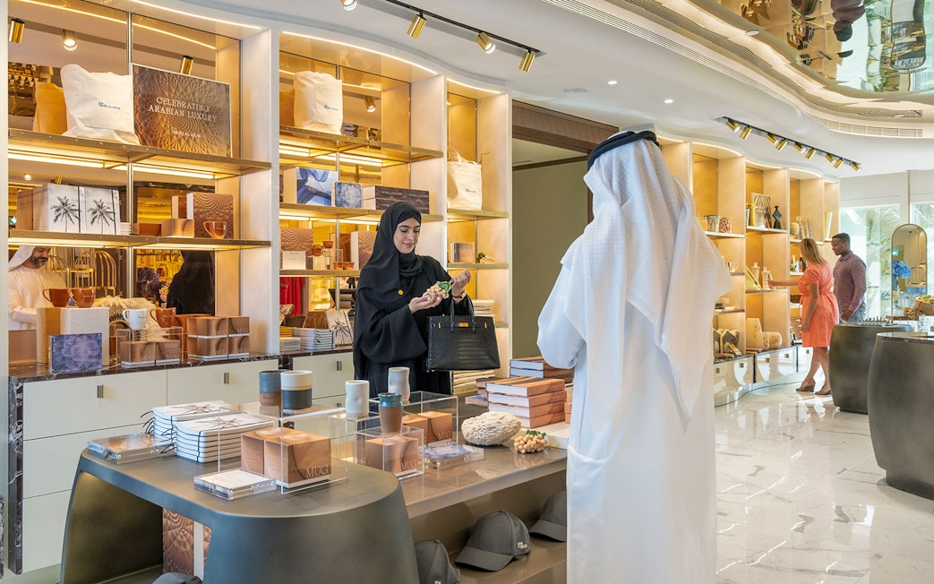 Tourists exploring luxury items at UMA Lounge gift shop during Inside Burj Al Arab Tour in Dubai.